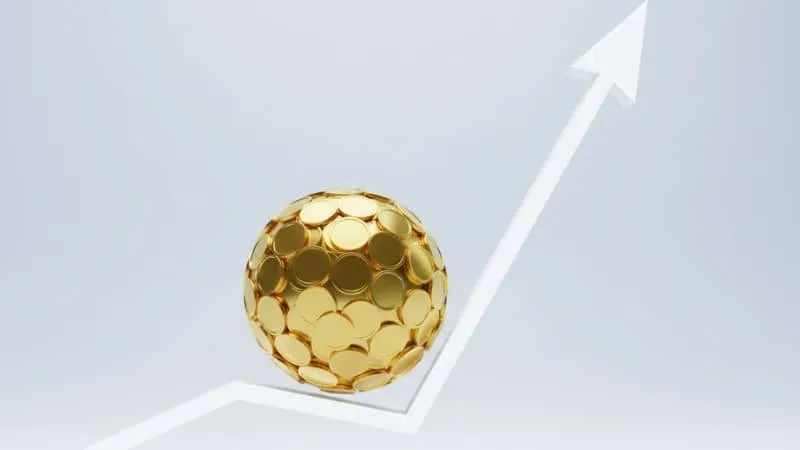 Uma ilustração conceitual em 3D de uma "bola de neve" de moeda de ouro rolando por uma linha de gráfico ascendente.